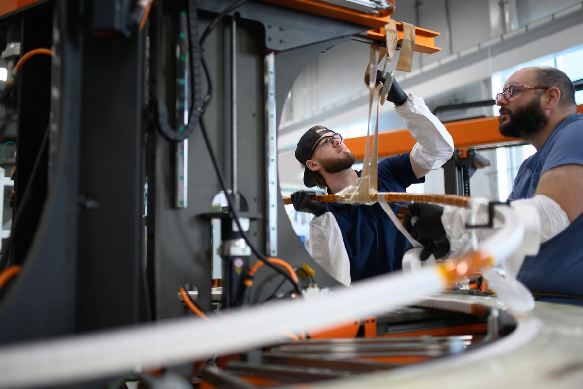 Two workers manufacture a superconducting cable at Commonwealth Fusion Systems' magnet factory.