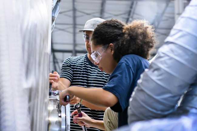 Two people wearing safety glasses working on bolting hardware in the factory